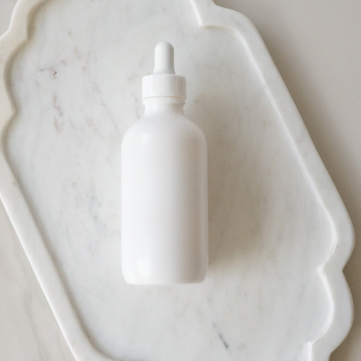 White dropper bottle on a marble surface