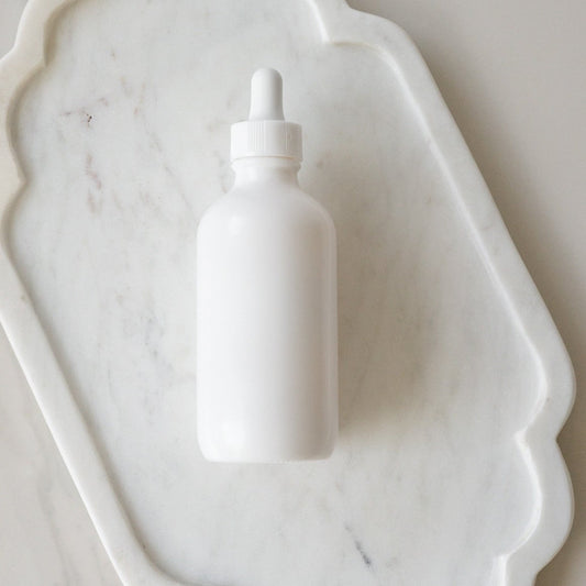 White dropper bottle on a marble surface